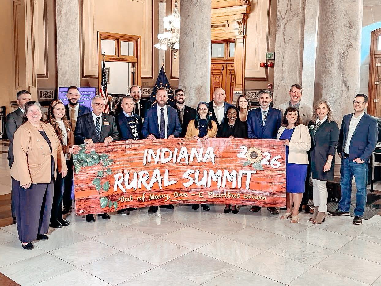 Photograph of House and Senate candidates with Michelle Higgs at the Statehouse, holding the Indiana Rural Summit banner at a press conference